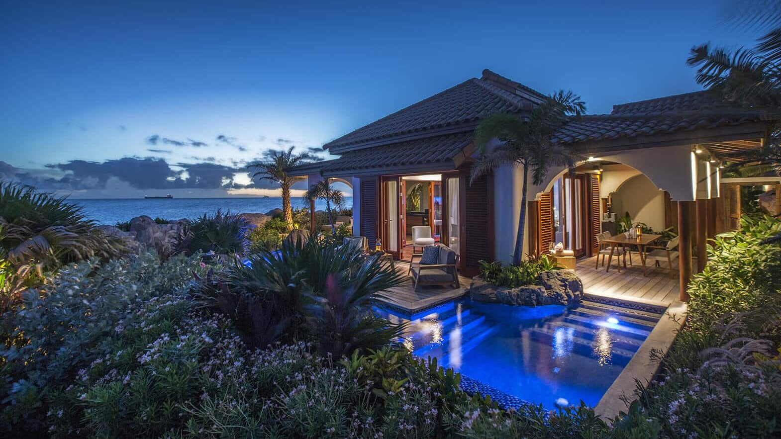 Baoase Curacao villa courtyard at dusk with private pool and lanterns.