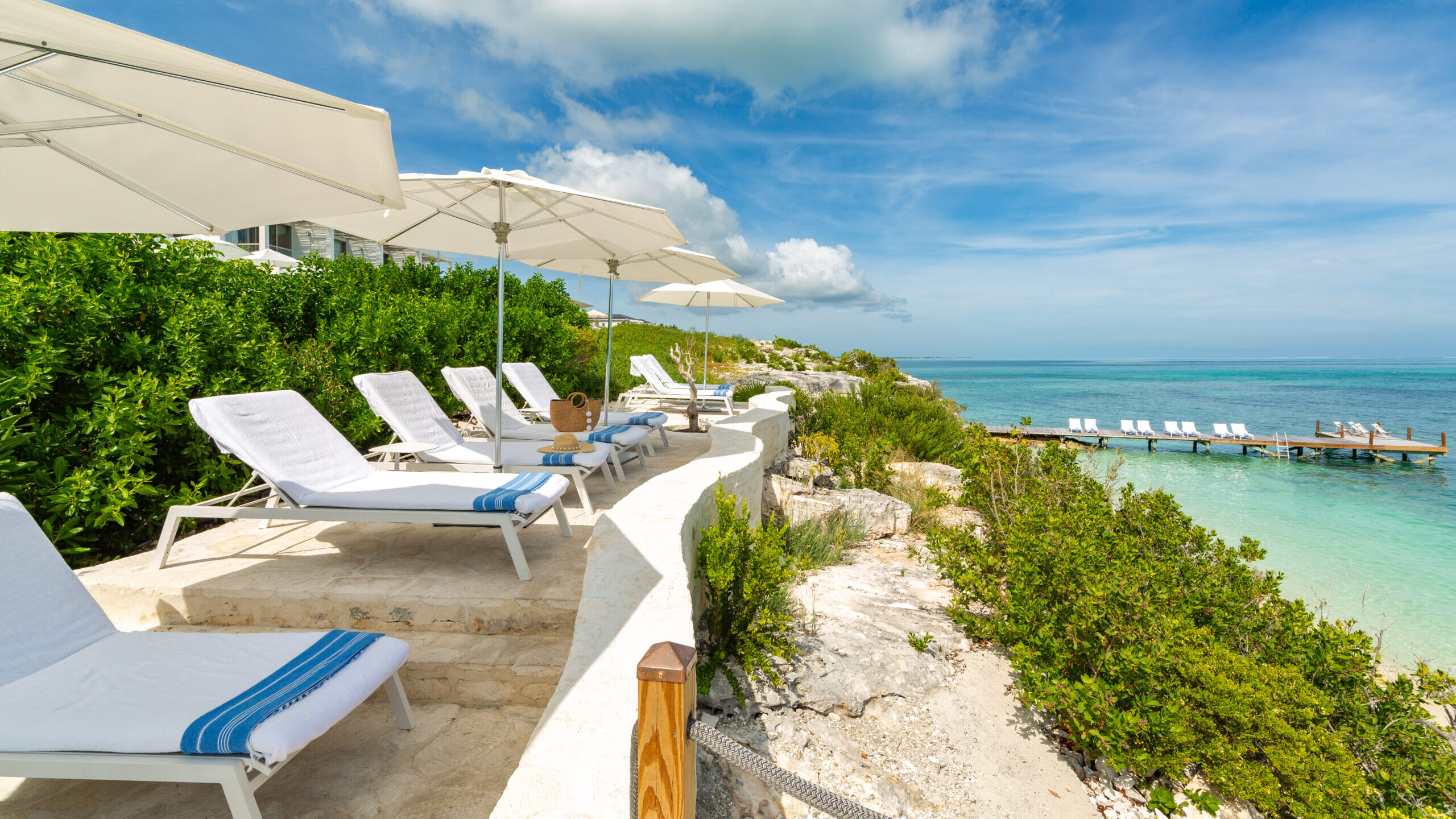 Limestone path along a cliff to a private loungers above turquoise water at Rock House Turks and Caicos