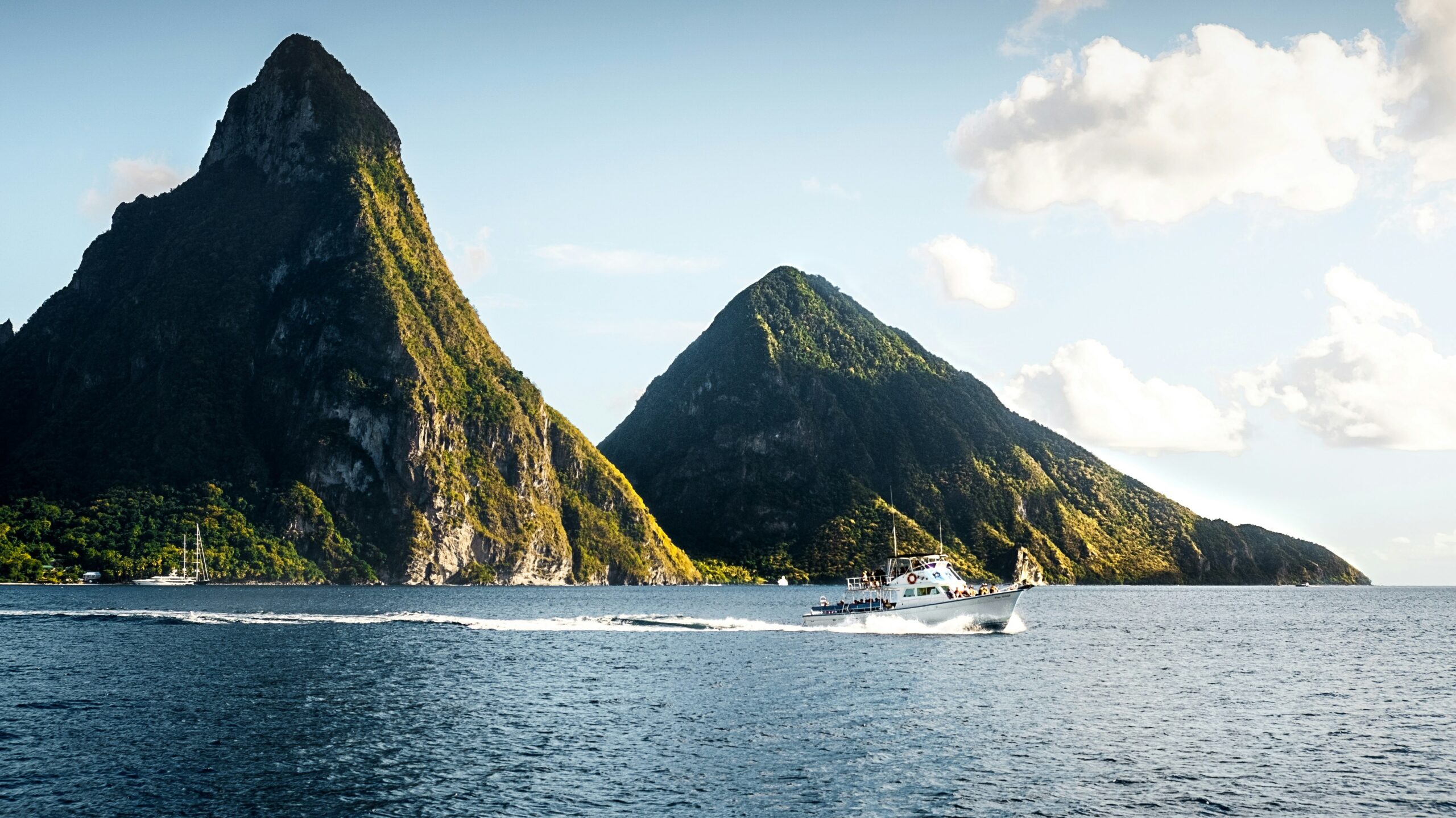 A boat glides through the water, with the Pitons rising in the background on a St. Lucia adults only trip.