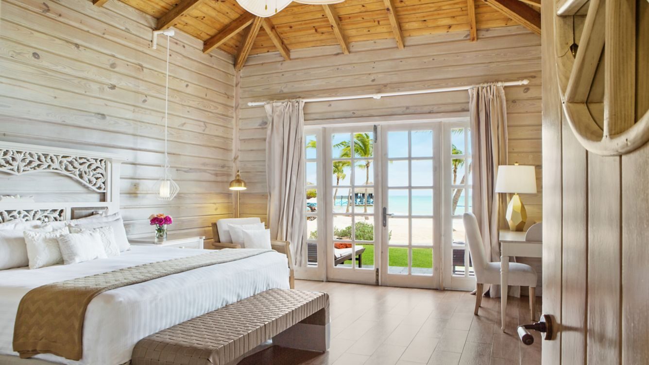 A stylish bedroom with wooden walls and a bed, situated in the oceanfront Monarch Villa at Sanctuary Cap Cana.